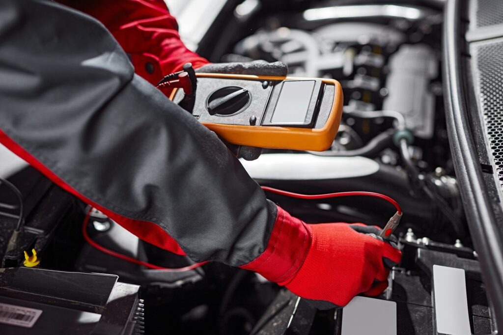 Crop male technician checking car battery